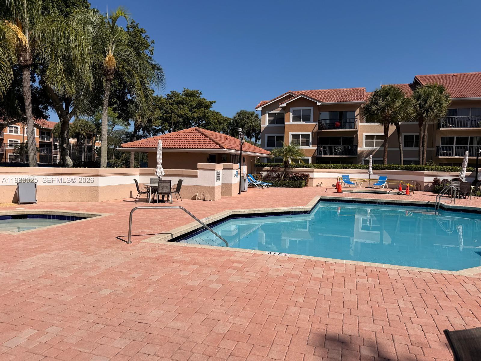 8821 Wiles Road, Unit 108 Coral Springs, FL 33067 - Photo 24 of 46 a view of a swimming pool with a lounge chairs
