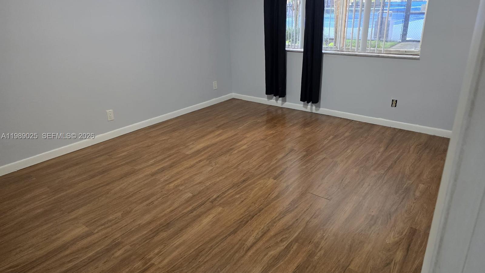 8821 Wiles Road, Unit 108 Coral Springs, FL 33067 - Photo 7 of 46 a view of an empty room with wooden floor and a window