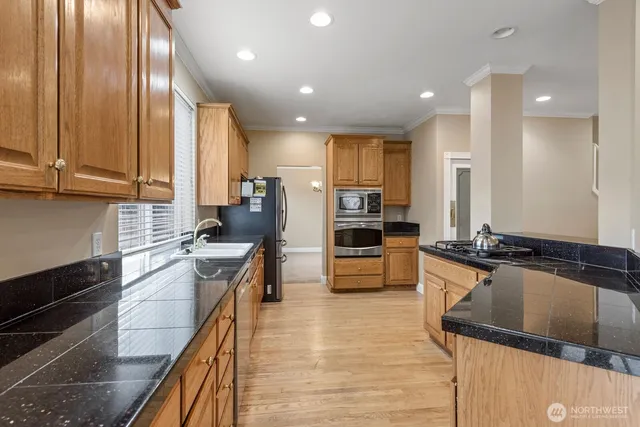 a kitchen with stainless steel appliances granite countertop sink stove and refrigerator
