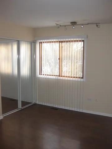 an empty room with wooden floor closet and windows