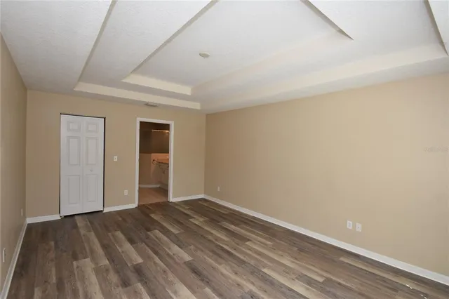 a view of an empty room with wooden floor and closet