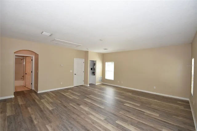 a view of an empty room with window and wooden floor