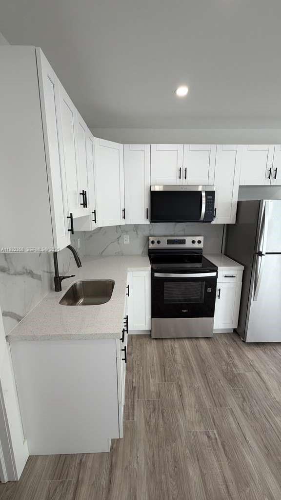 935 Jefferson Avenue, Unit 10 Miami Beach, FL 33139 - Photo 3 of 11 a kitchen with wooden cabinets and white appliances
