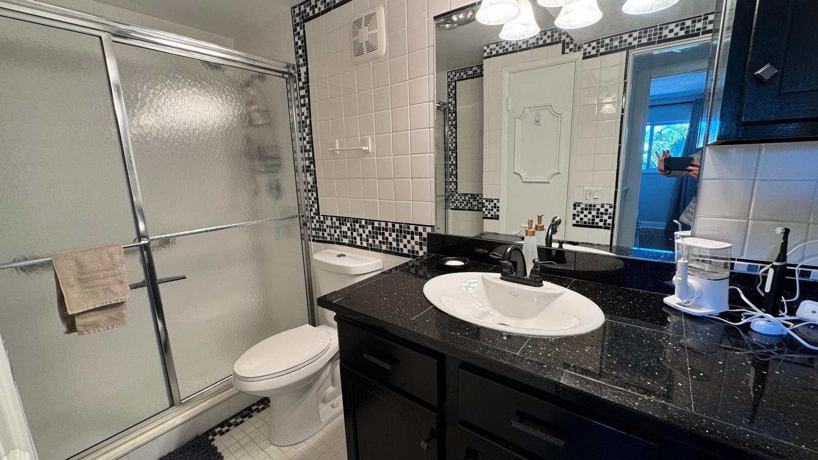 2151 Northeast 42nd Court, Unit 221 Lighthouse Point, FL 33064 - Photo 13 of 31 a bathroom with a sink vanity granite toilet shower and a mirror