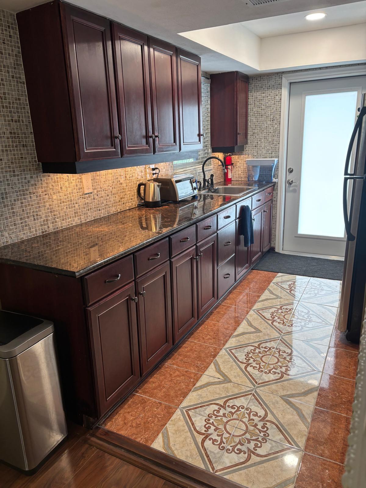 2151 Northeast 42nd Court, Unit 221 Lighthouse Point, FL 33064 - Photo 4 of 31 a kitchen with kitchen island granite countertop wooden cabinets a sink and dishwasher