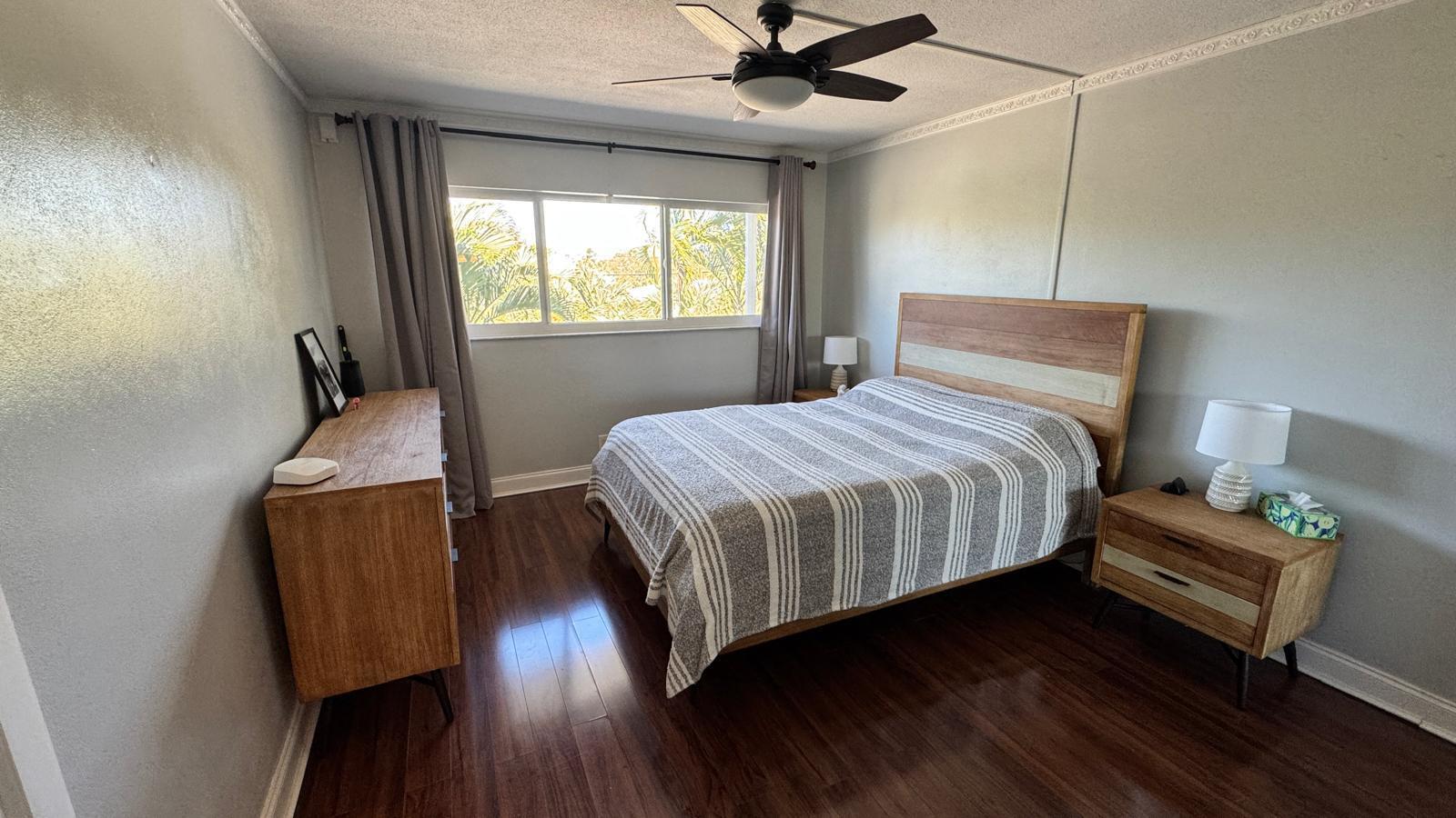 2151 Northeast 42nd Court, Unit 221 Lighthouse Point, FL 33064 - Photo 10 of 31 a bedroom with a bed and wooden floor