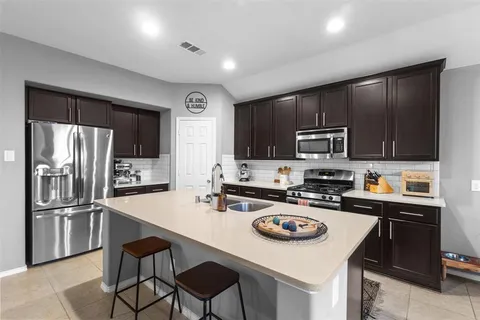 a kitchen with kitchen island a sink stove and refrigerator