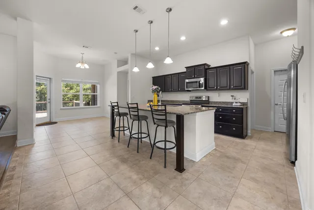 a kitchen with stainless steel appliances granite countertop a stove top oven a sink a counter top space cabinets and a window