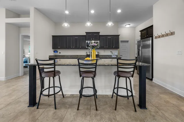 a view of a kitchen with kitchen island stainless steel appliances refrigerator sink dining table and chairs