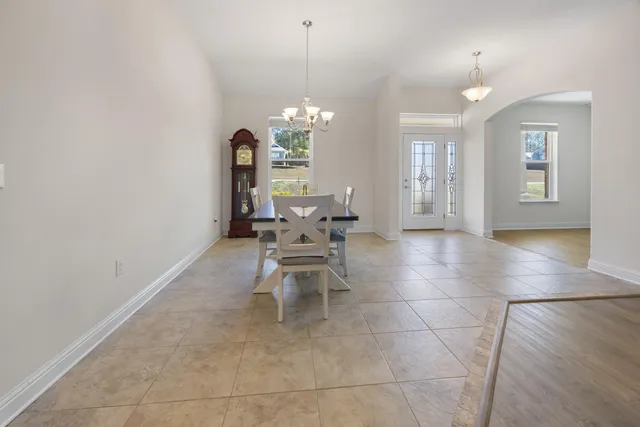 a dining room with chandelier and wooden floor
