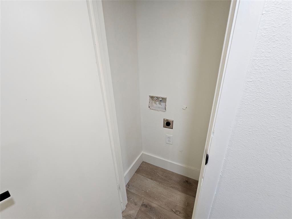 1725 R Avenue, Unit 1725 Plano, TX 75074 - Photo 17 of 20 Dedicated laundry alcove featuring neutral white walls, white trim, wood-finish flooring, a wall-mounted dryer vent, and plumbing hookups