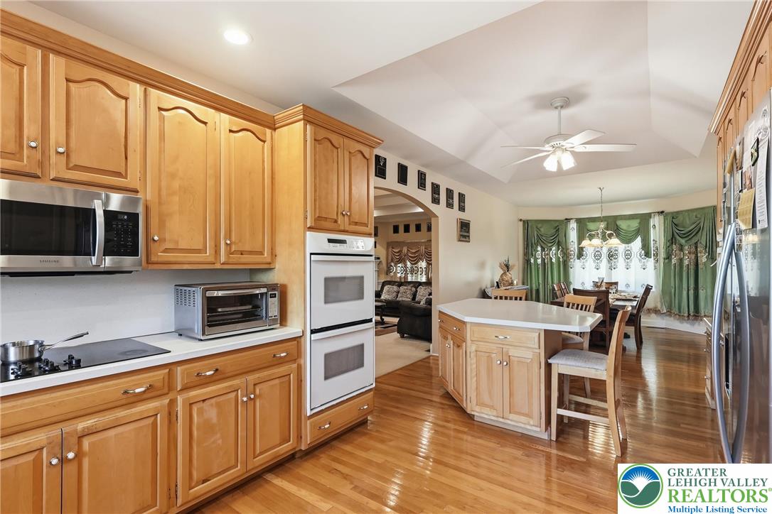 5217 Cider Press Road Schnecksville, PA 18078 - Photo 21 of 54 a kitchen with stainless steel appliances granite countertop a stove top oven a sink dishwasher and white cabinets with wooden floor