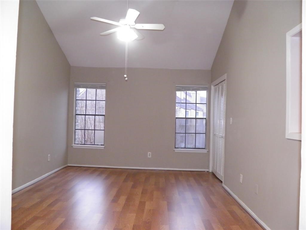9901 Sharpcrest Street, Unit D1 Houston, TX 77036 - Photo 2 of 8 an empty room with wooden floor chandelier fan and windows