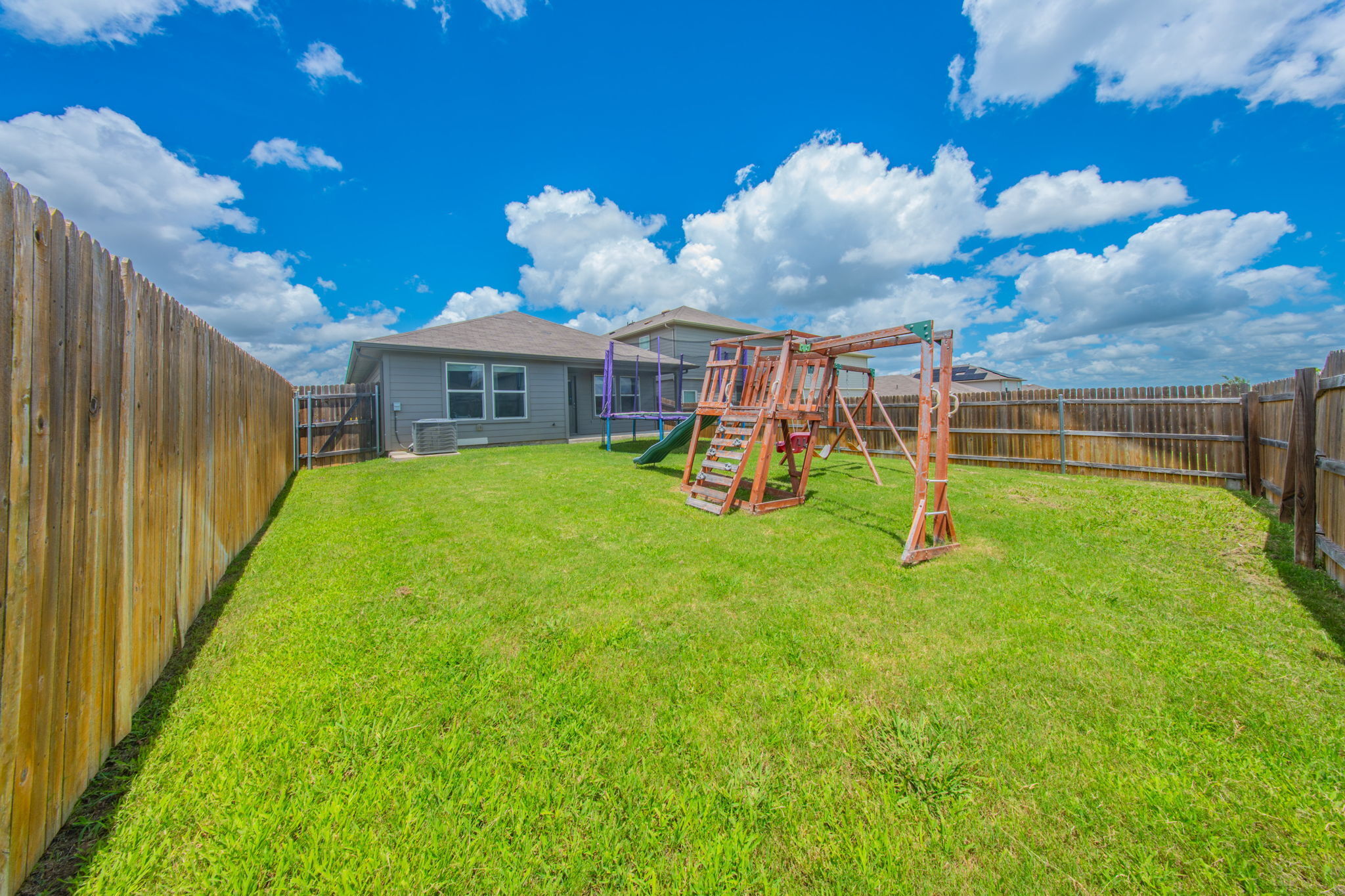 14903 Tuff Road Manor, TX 78653 - Photo 23 of 25 A spacious backyard with a playset and trampoline for endless outdoor enjoyment.