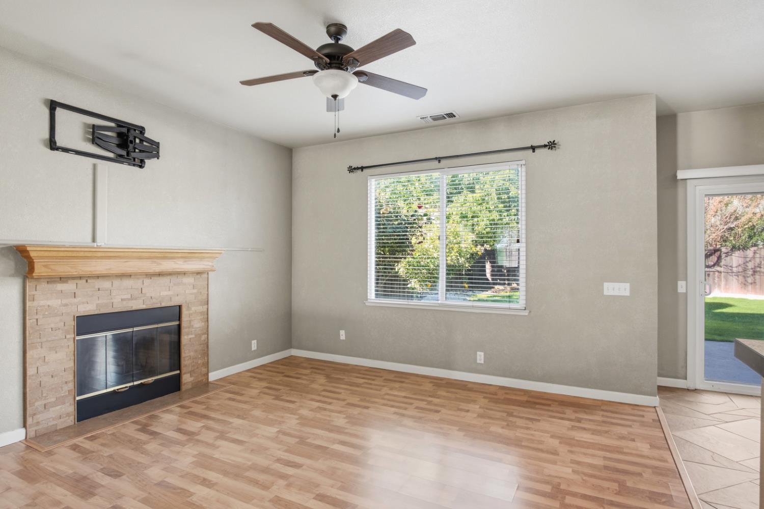 2213 Lionudakis Court Modesto, CA 95355 - Photo 11 of 38 an empty room with windows fireplace and wooden floor