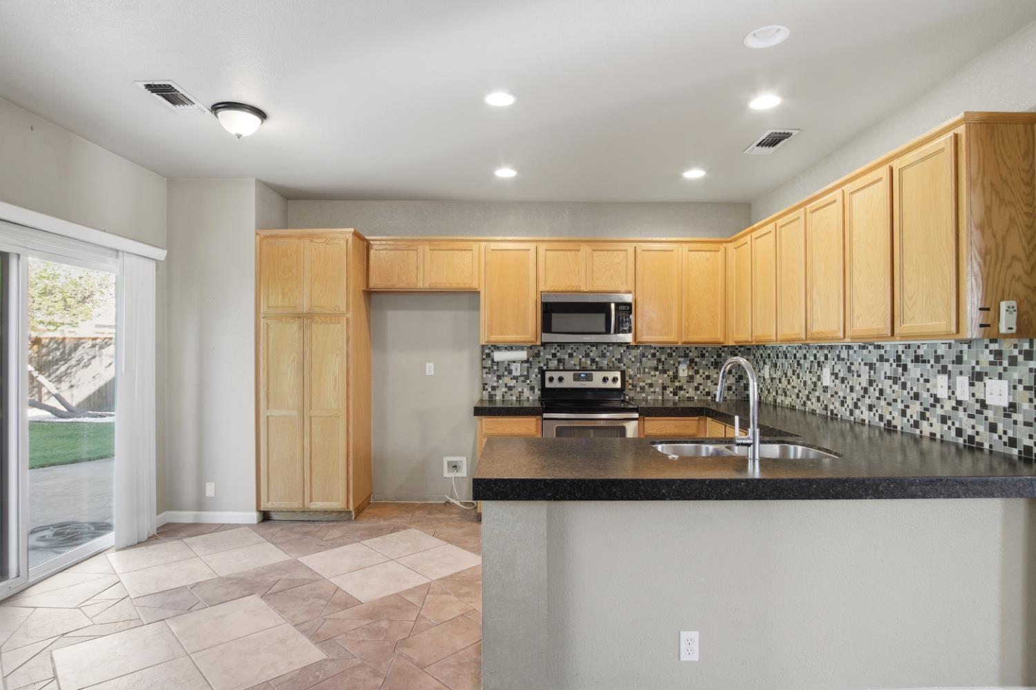 2213 Lionudakis Court Modesto, CA 95355 - Photo 14 of 38 a kitchen with stainless steel appliances granite countertop a stove a sink and a refrigerator