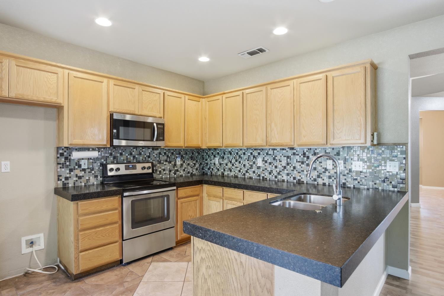 2213 Lionudakis Court Modesto, CA 95355 - Photo 16 of 38 a kitchen with stainless steel appliances granite countertop a sink a stove and a microwave