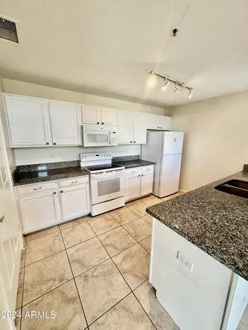 a kitchen with stainless steel appliances granite countertop a stove a sink and a refrigerator