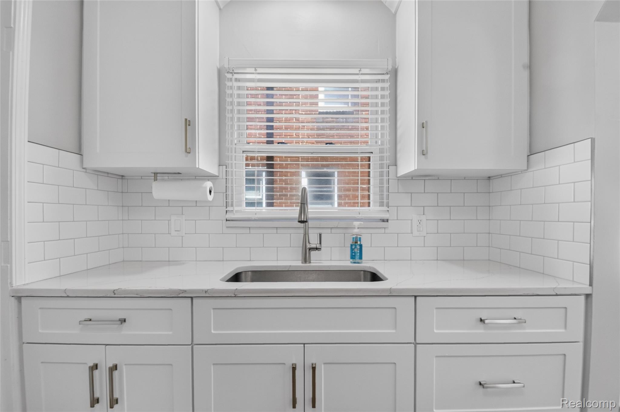12972 Callender Street Southgate, MI 48195 - Photo 15 of 40 Kitchen sink area featuring a stainless steel undermount sink, white subway tile backsplash, white shaker-style cabinetry, white countertops, and a modern pull-down faucet