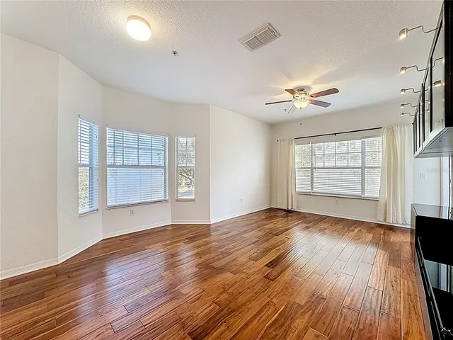 a view of empty room with wooden floor and fan