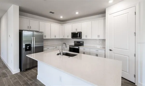 a kitchen with stainless steel appliances a refrigerator sink and white cabinets