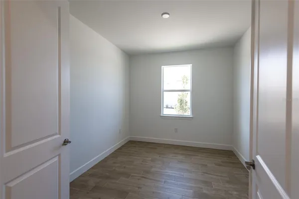 an empty room with wooden floor and window