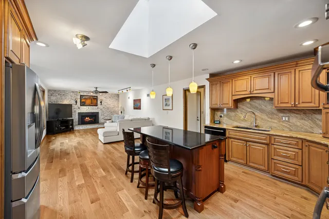 a kitchen with stainless steel appliances granite countertop a refrigerator a oven a sink dishwasher and wooden cabinets with wooden floor