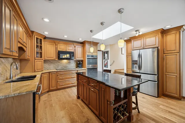 a kitchen with stainless steel appliances granite countertop a sink a stove top oven a counter space and cabinets