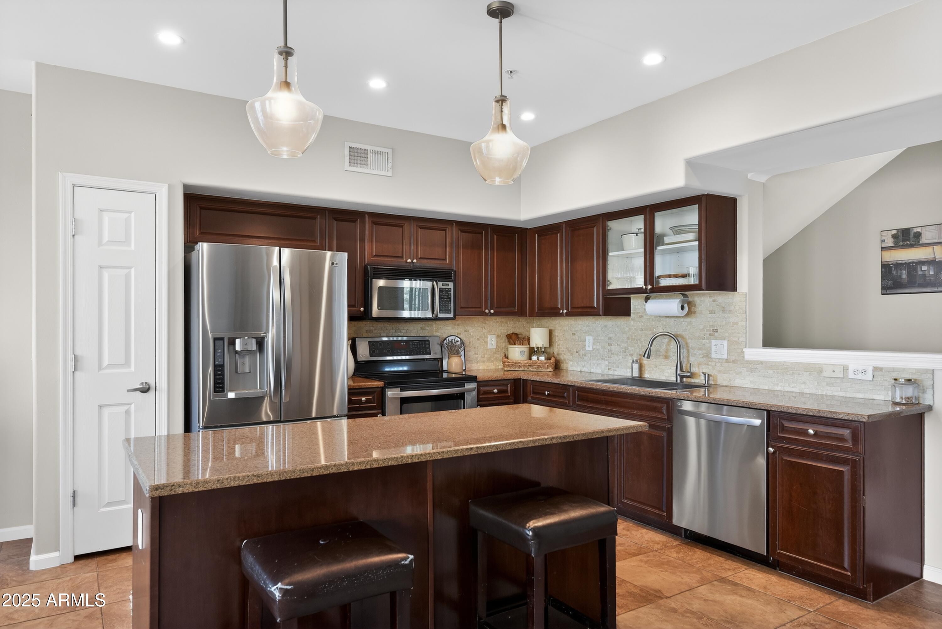 1920 East Bell Road, Unit 1079 Phoenix, AZ 85022 - Photo 11 of 29 a kitchen with stainless steel appliances a sink a stove a refrigerator cabinets and chairs