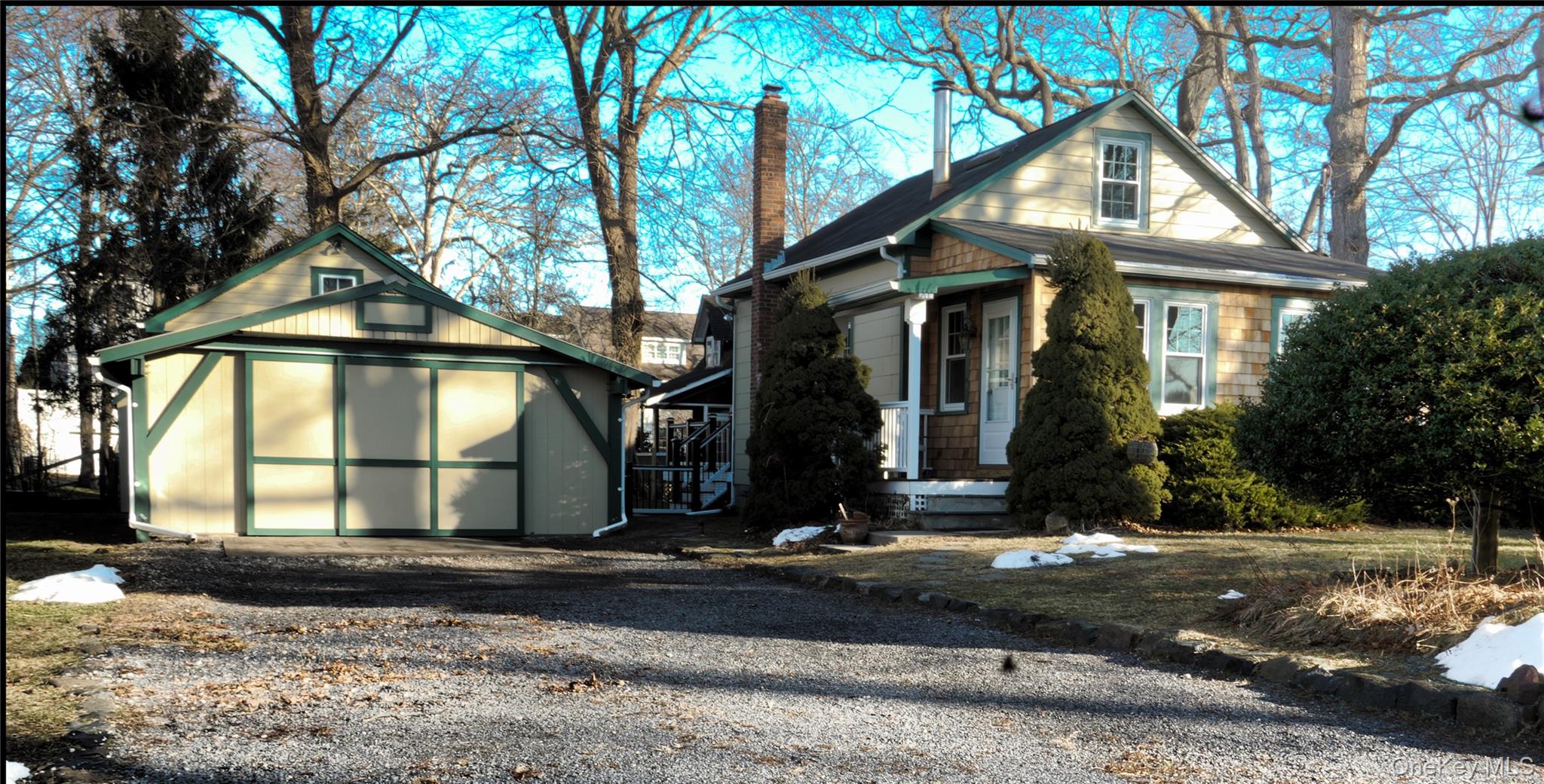 View of front of home featuring a chimney, a storage shed, and gravel driveway