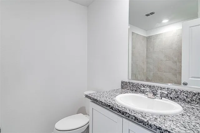 a bathroom with a granite countertop sink toilet and mirror