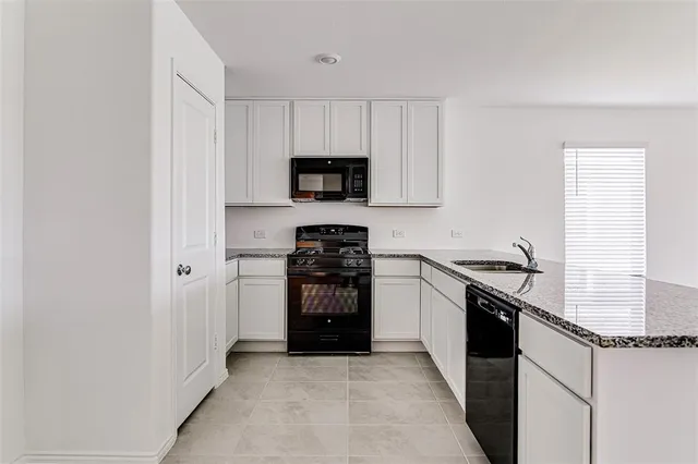 a kitchen with granite countertop a stove sink and refrigerator