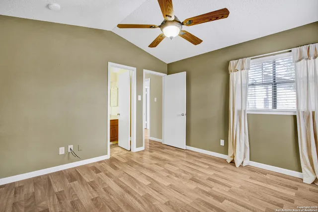 an empty room with wooden floor fan and windows