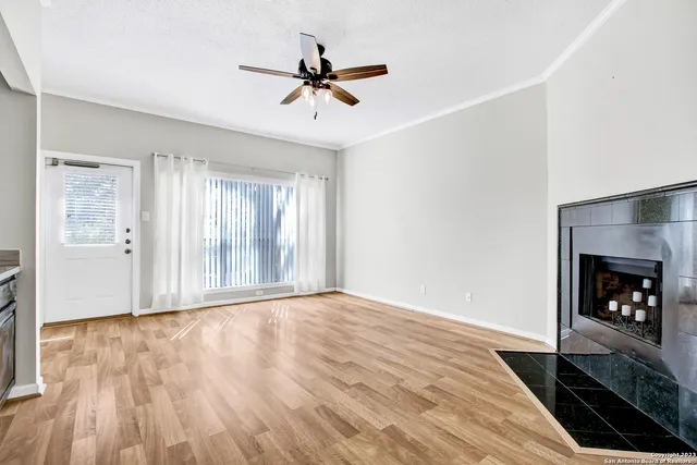 a view of an empty room with wooden floor fireplace and a window