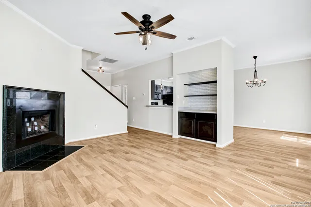 a view of a livingroom with a fireplace a ceiling fan and wooden floor