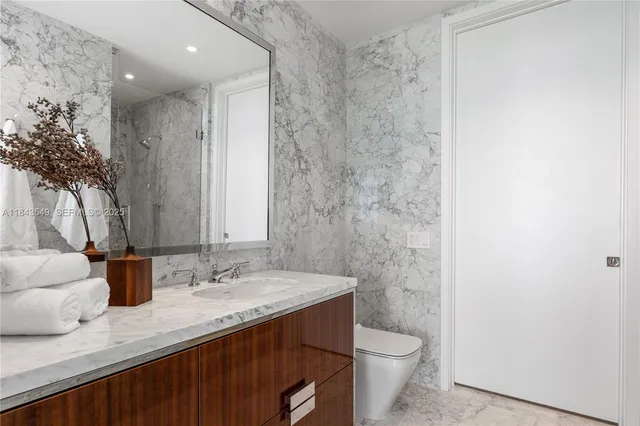 a bathroom with a granite countertop sink a toilet and a mirror