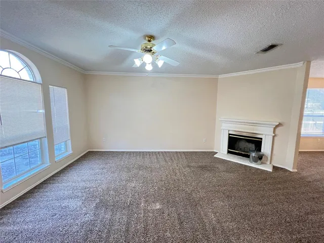 a view of an empty room with chandelier fan and fire place
