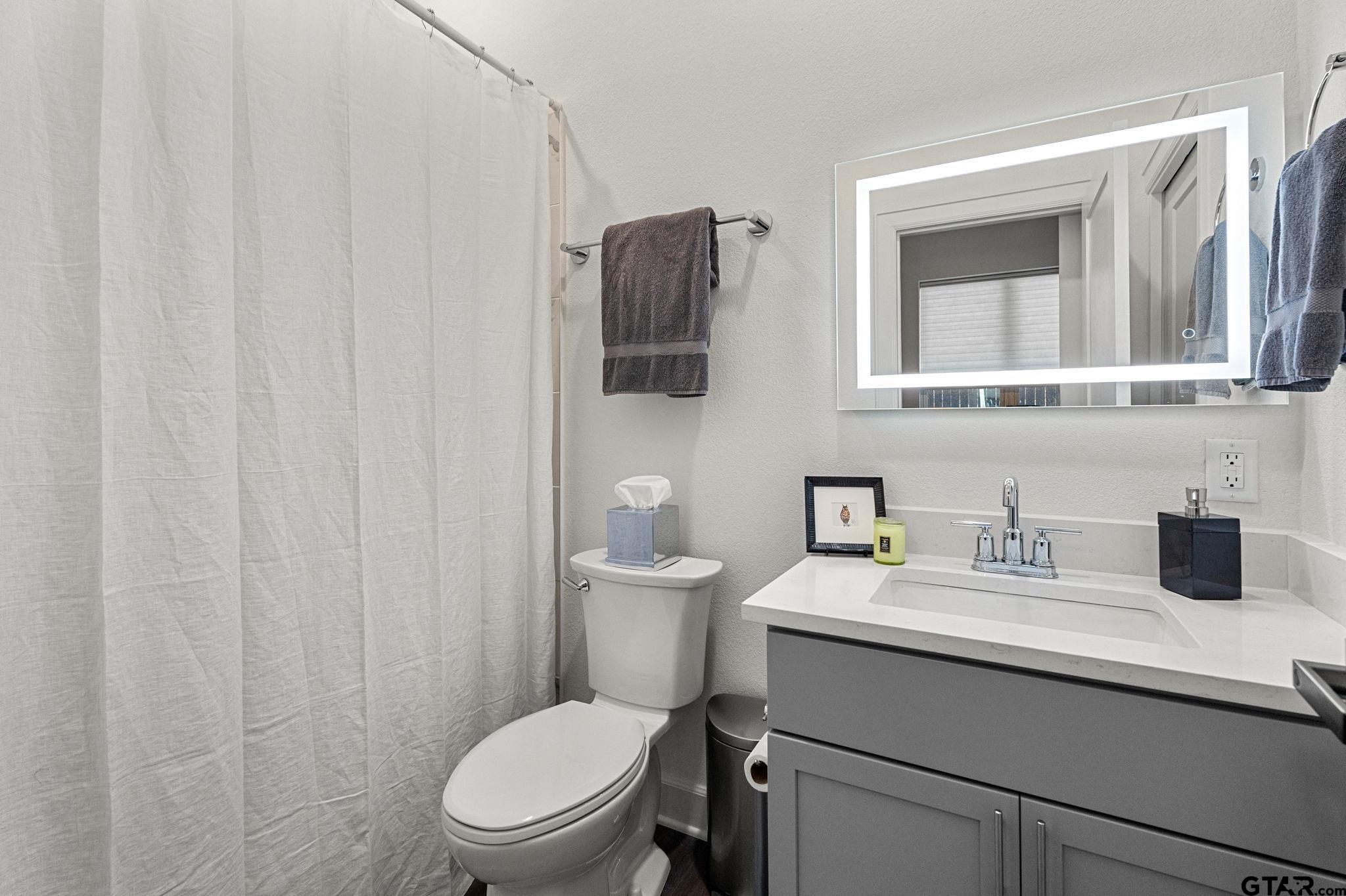 546 West Erwin Street Tyler, TX 75702 - Photo 6 of 31 a bathroom with a toilet a sink and mirror