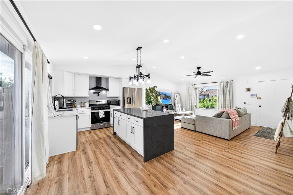 5050 Brooklawn Place Riverside, CA 92504 - Photo 12 of 44 a large living room with stainless steel appliances kitchen island granite countertop wooden floor and a view of kitchen