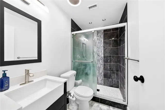 a bathroom with a sink a toilet and shower