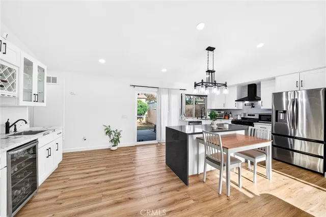 a kitchen with granite countertop a refrigerator stove a oven and white cabinets with wooden floor