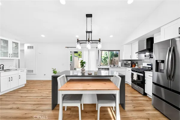 a kitchen with stainless steel appliances a dining table chairs stove and refrigerator