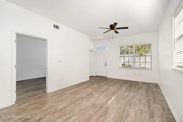 an empty room with windows and fan