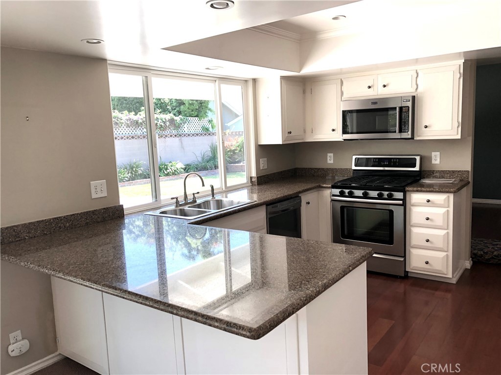 11402 Donovan Road Los Alamitos, CA 90720 - Photo 9 of 44 a kitchen with granite countertop a stove and a microwave