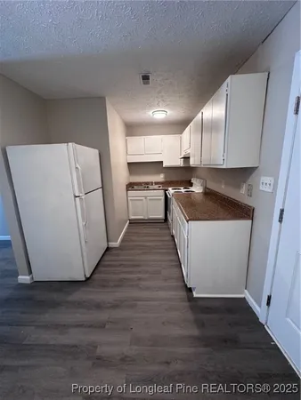 a kitchen with a sink a refrigerator a microwave and cabinets