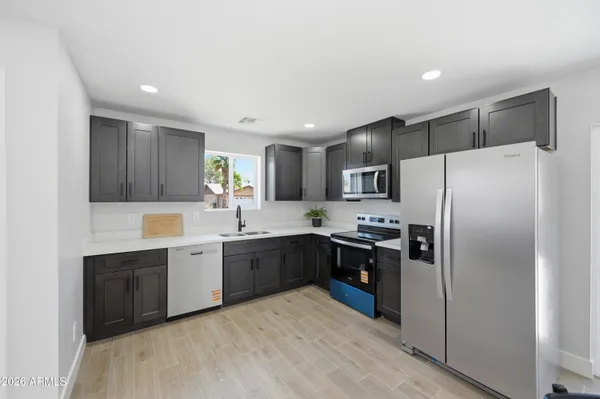 a large kitchen with cabinets a sink and stainless steel appliances