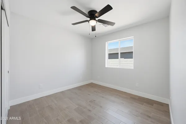 an empty room with wooden floor and ceiling fan