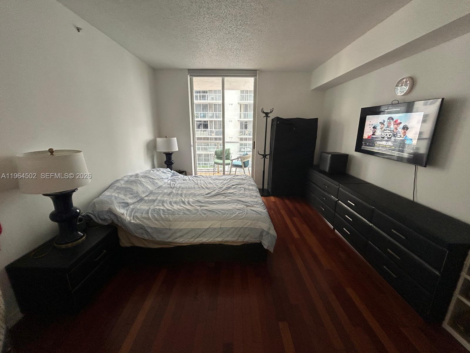 5077 Northwest 7th Street, Unit 1012 Miami, FL 33126 - Photo 10 of 15 a bedroom with a bed dresser and a flat screen tv