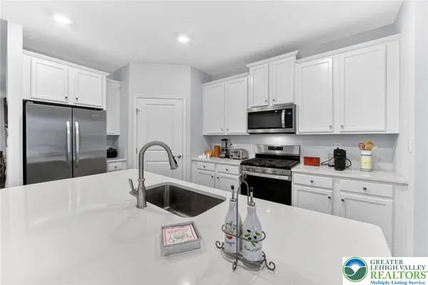 a kitchen with kitchen island granite countertop a sink a stove a refrigerator cabinets and a dining table
