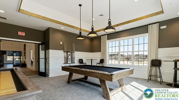 a living room with a table a rug and kitchen view